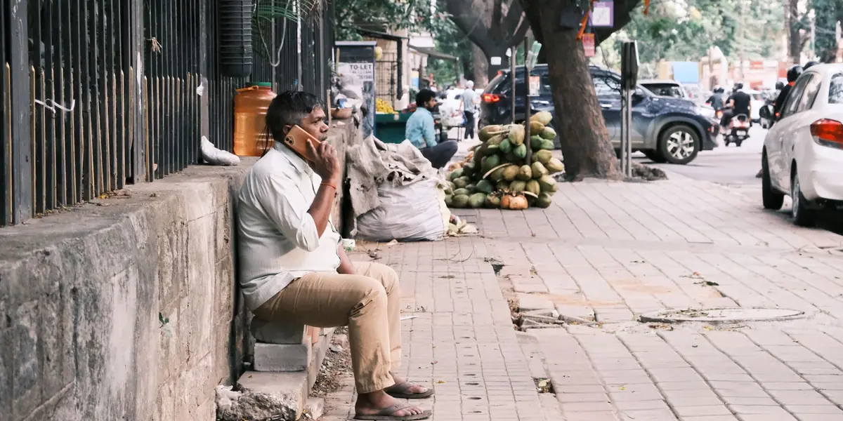 A man taking a phone call on a city pavement