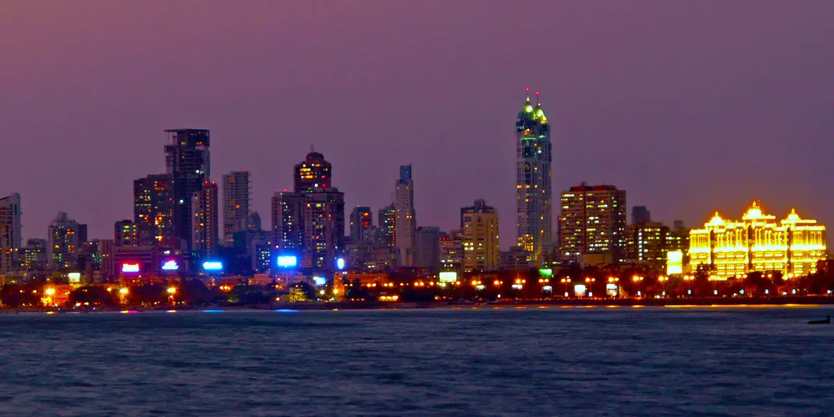 Mumbai skyline lit up at dusk across the water