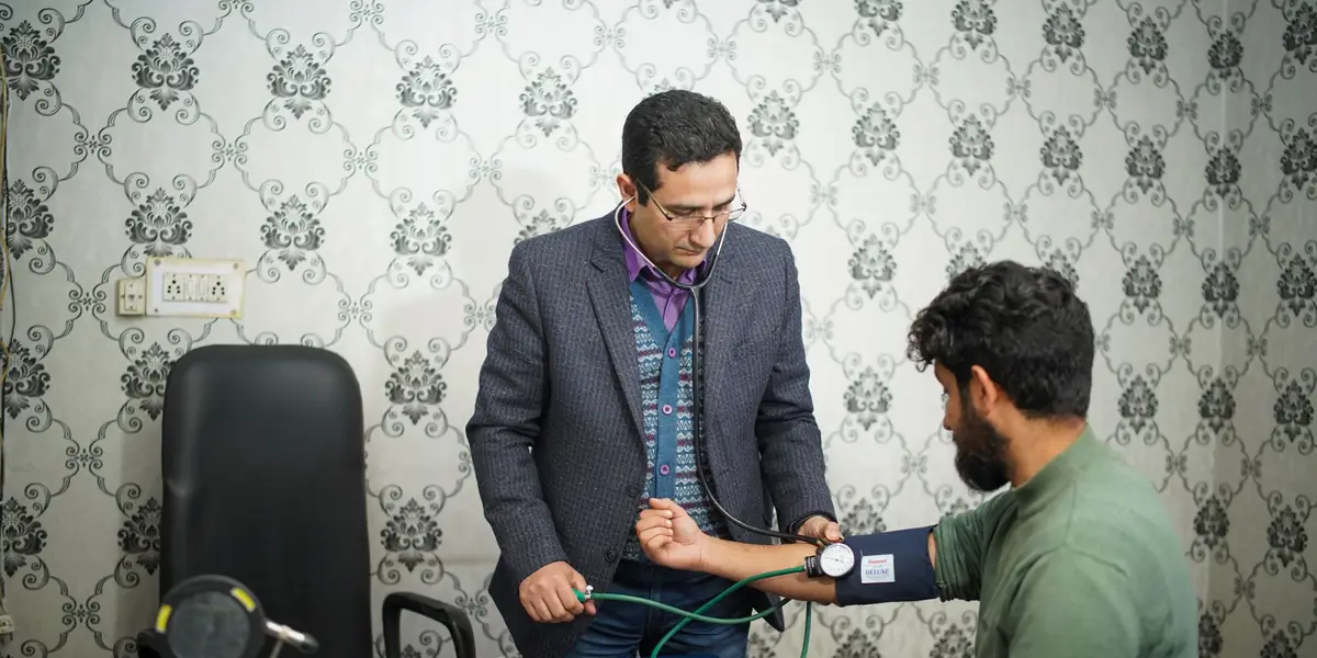 A doctor checking a patient's blood pressure in a clinic